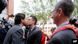 Kevin Patterson, left, and David Larance kiss after exchanging vows, as Rev. John Dorhaer, who performed the ceremony, stands at right, Oct. 17, 2014, in Phoenix, Arizona. 