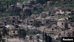  이스라엘 측에서 바라본 레바논 접경 지역의 파손된 건물들과 서 있는 장갑차의 모습.