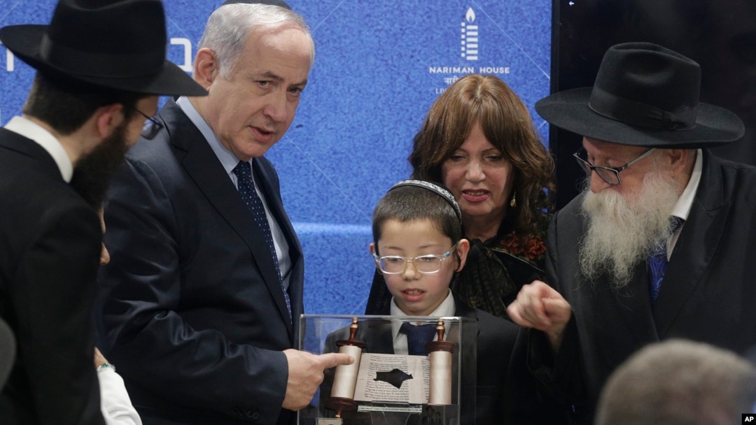 Prime Minister Netanyahu receives a memento from a young boy whose parents were killed during a terror attack as he unveils plans for a state-of-the-art Living Memorial in commemoration of the victims of the Mumbai attacks at the Chabad House in Mumbai, Jan. 18, 2018.