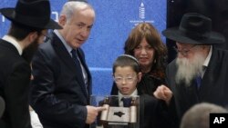 Prime Minister Netanyahu receives a memento from a young boy whose parents were killed during a terror attack as he unveils plans for a state-of-the-art Living Memorial in commemoration of the victims of the Mumbai attacks at the Chabad House in Mumbai, Jan. 18, 2018.