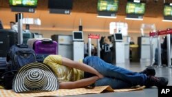 Un pasajero de Viva Air duerme junto a sus maletas luego de que la aerolínea de bajo costo suspendiera sus operaciones en el Aeropuerto Internacional El Dorado de Bogotá, el 28 de febrero de 2023. 