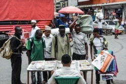 FILE - People look at newspapers without adhering to the rules of social distancing despite the confirmed COVID-19 coronavirus cases in Dar es Salaam, Tanzania, April 16, 2020.