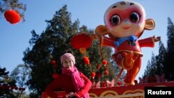 一名女子在北京地坛公园前为迎接中国新年猴年到来树立的猴像前留影 （2016年2月）