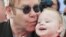 El cantante pop Elton John besa a un bebé en un hospicio de Ukrania. John y su pareja David Furnish anunciaron la llegada de un segundo hijo.