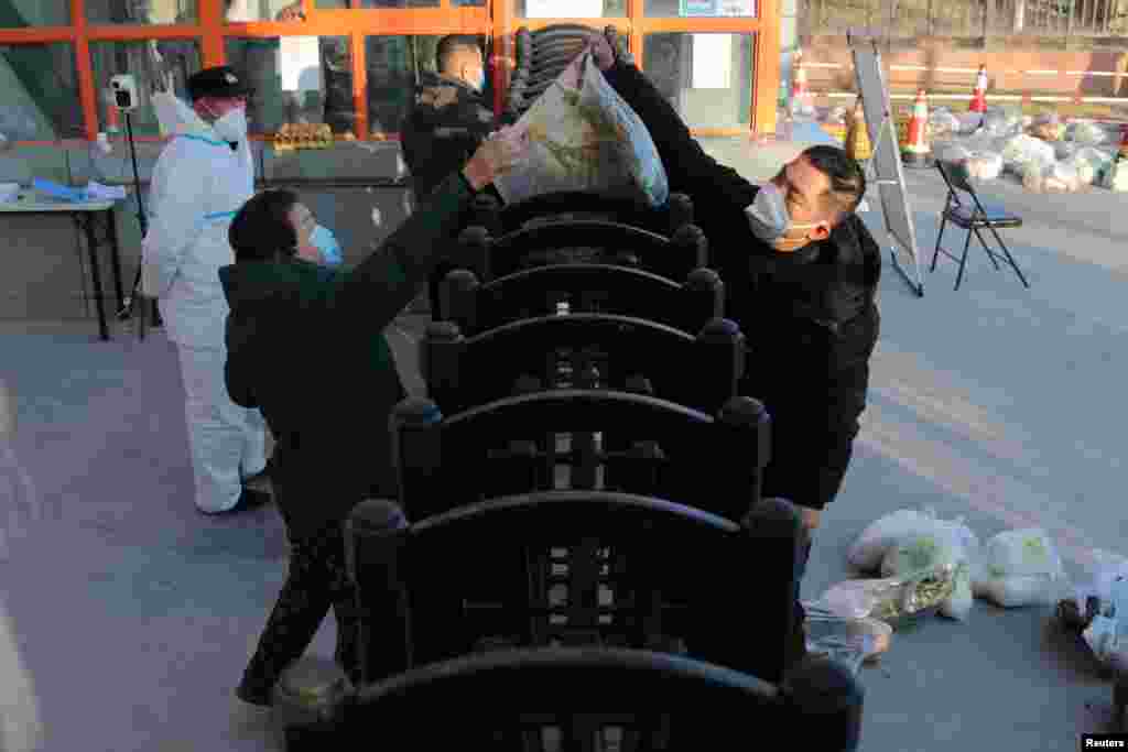 A worker delivers food supplies to residents at a residential compound under lockdown following a COVID-19 outbreak in Xian, Shaanxi province, China, Dec. 29, 2021.