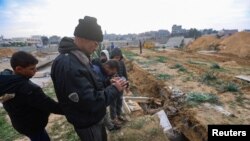 FILE - Palestinians check damaged graves at a cemetery following an Israeli raid, amid the ongoing conflict between Israel and the Palestinian Islamist group Hamas, in Khan Younis in the southern Gaza Strip, January 17, 2024.