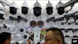 FILE - Visitors look at the surveillance cameras by China's telecoms equipment giant Huawei on display at the China Public Security Expo in Shenzhen, China's Guangdong province, Oct. 29, 2019.