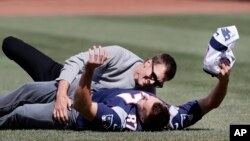 New England Patriots quarterback Tom Brady, top, tackles teammate Rob Gronkowski after he ran with Brady's recovered Super Bowl jersey as they joke around during Boston Red Sox Home Opening Day ceremonies at Fenway Park, April 3, 2017, in Boston.