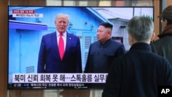 Orang-orang menonton siaran berita TV yang menampilkan gambar Pemimpin Korea Utara Kim Jong Un dan Presiden AS Donald Trump (kiri), di Stasiun Kereta Seoul, 31 Desember 2019. 