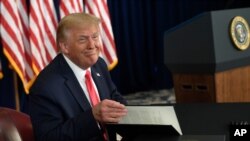 트럼프 대통령이 8일 '트럼프 내셔널 골프 클럽'에서 기자회견을 열고 행정 명령에 서명한 뒤 미소 짓고 있다. 