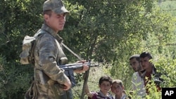 A Turkish soldier stands by as a group of Syrians wait for the authorization to enter Turkey near the Turkish village of Guvecci in Hatay province, Turkey, which borders Syria, June 9, 2011