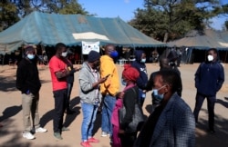 FILE - People queue to be vaccinated against COVID-19 at a clinic in Harare, Zimbabwe, July 8, 2021.