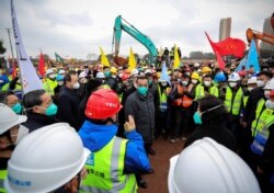 Chinese Premier Li Keqiang, wearing a mask, talks with staff members as he visits the construction site where a hospital is being built to treat patients of a new coronavirus, following the outbreak, on the outskirts of Wuhan, China, Jan. 27, 2020.