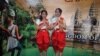 ស្រ្តី​ខ្មែរ​ឈរ​នៅ​ក្បែរ​ផ្ទាំង​បដា​ដែល​ផ្សព្វផ្សាយ​អំពី​ទេសចរណ៍​នៅ​ប្រទេស​កម្ពុជា។ (ម៉ែន គឹមសេង/VOA)