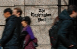 FILE - People walk past the home of The Washington Post newspaper, in downtown Washington, Feb. 21, 2019.