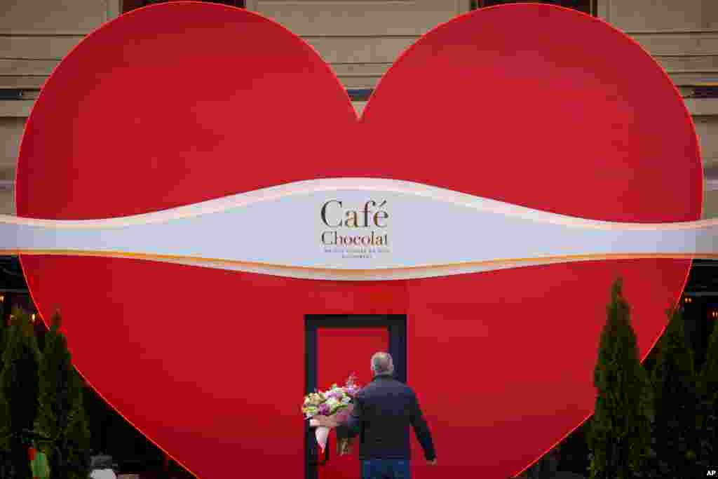 A man holds flowers as he walks to a cafe decorated for Valentine&#39;s Day, in Bucharest, Romania.