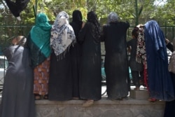 FILE - Internally displaced Afghan women, who fled from the northern province due to battle between Taliban and Afghan security forces, gather to receive free food being distributed by Shiite men at Shahr-e-Naw Park in Kabul, August 13, 2021.