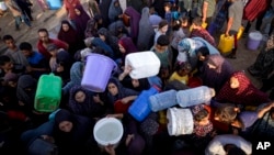 FILE - Palestinians displaced by the Israeli bombardment of the Gaza Strip queue for water at a makeshift tent camp in the southern town of Khan Younis, July 1, 2024.