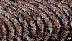 FILE - Men and women pump their fists in the air and chant "Defend!" as they carry propaganda slogans calling for reunification of their country during the "Pyongyang Mass Rally on the Day of the Struggle Against the U.S."