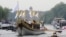 This photo provided by LOCOG shows the royal barge Gloriana carrying Olympic flame burning in the cauldron as it makes its way down the River Thames towards Richmond Bridge during the final day of the Olympic torch relay in London, July 27, 2012. 
