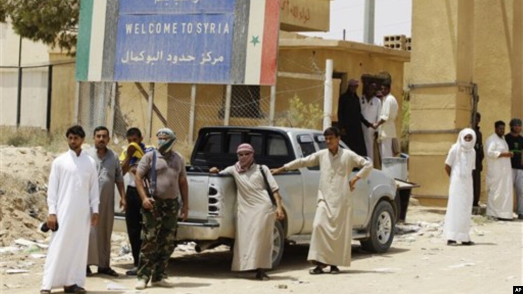 Armed Syrian rebels stand guard as refugees flee Syria at border crossing near Qaim, Iraq, July 25, 2012.