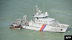 FILE - This handout photograph taken and released by the French Marine Nationale on Aug. 5, 2019, shows migrants sitting in an inflatable dinghy rescued by French coast guards while trying to cross the Channel between France and Britain.