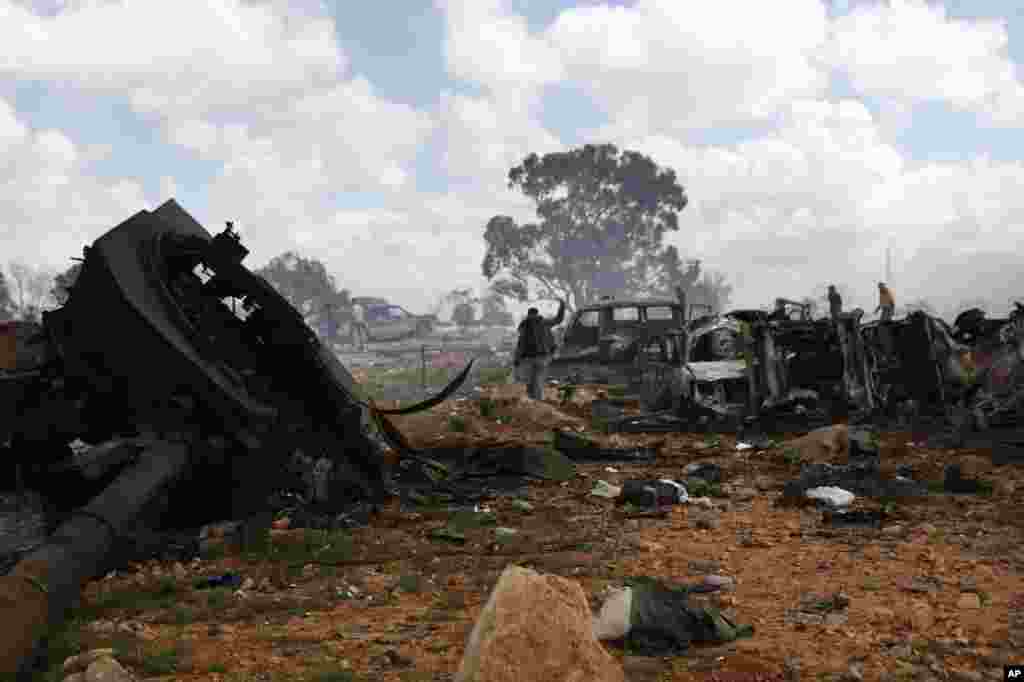 A rebel fighter flashes the victory sign as he walks through the scene of what residents said was a French airstrike against Muammar Gaddafi's forces early on Sunday morning on the southern outskirts of Benghazi in northeastern Libya, March 20, 2011.The 