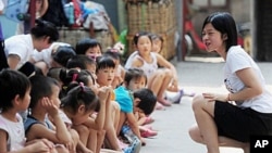 A group of Chinese children, whose migrant parents are unable to afford the kindergarten or pre-school education in China's capital, gather with volunteers in Beijing, 7 July 2010