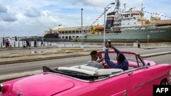Un hombre toma fotografías del submarino de propulsión nuclear Kazan (izq.) y del remolcador fragata Almirante Gorshkov (der.), parte del destacamento naval ruso que visita Cuba, después de su llegada al puerto de La Habana el 12 de junio de 2024. 