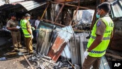 Sri Lankan security officers inspect vandalized shops owned by Muslims in Minuwangoda, a suburb of Colombo, May 14, 2019. 