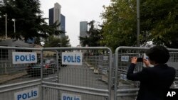 Un journaliste filme derrière une barrière bloquant la route menant au consulat d'Arabie saoudite à Istanbul, le 19 octobre 2018.