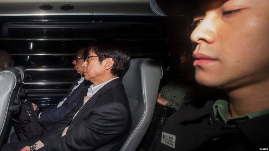 Mantan pimpinan Sun Hung Kai Properties Thomas Kwok (kiri) dan mantan Director Eksekutif Sun Hung Kai Properties Thomas Chan (tengah) duduk di dekat petugas setibanya di pengadilan tinggi Hong Kong (23/12).