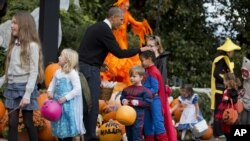 President Barack Obama pats a child dressed as Superman on the head during Halloween festivities near the South Portico of the White House in Washington, Oct. 31, 2014.