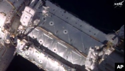 FILE - American astronauts Jeffrey Williams, left, and Kate Rubins take a spacewalk to hook up an International Space Station docking port, Aug. 19, 2016. NASA provided the image. The astronauts currently at the space station are taking a pair of spacewalks Friday and next week.