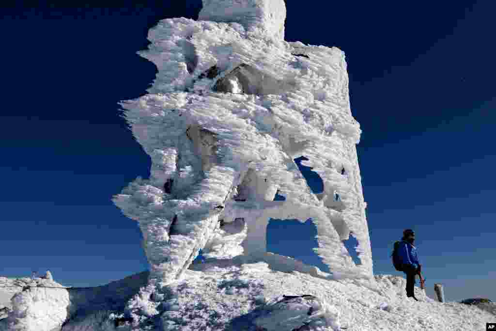 Douglas Ciampi of Westminster, Mass., stands next to a rime ice-covered antenna on the summit of Mount Washington, New Hampshire, Feb. 23, 2020.