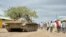 FILE - In this photo provided by the African Union Mission to Somalia (AMISOM), African Union (AU) soldiers from Uganda sit on their tank as residents walk past in the town of Bulomarer, in the Lower Shabelle region of Somalia, Aug. 31, 2014.