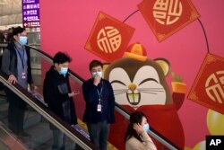 People wear face masks as they ride an escalator at the Hong Kong International Airport in Hong Kong, Jan. 21, 2020.