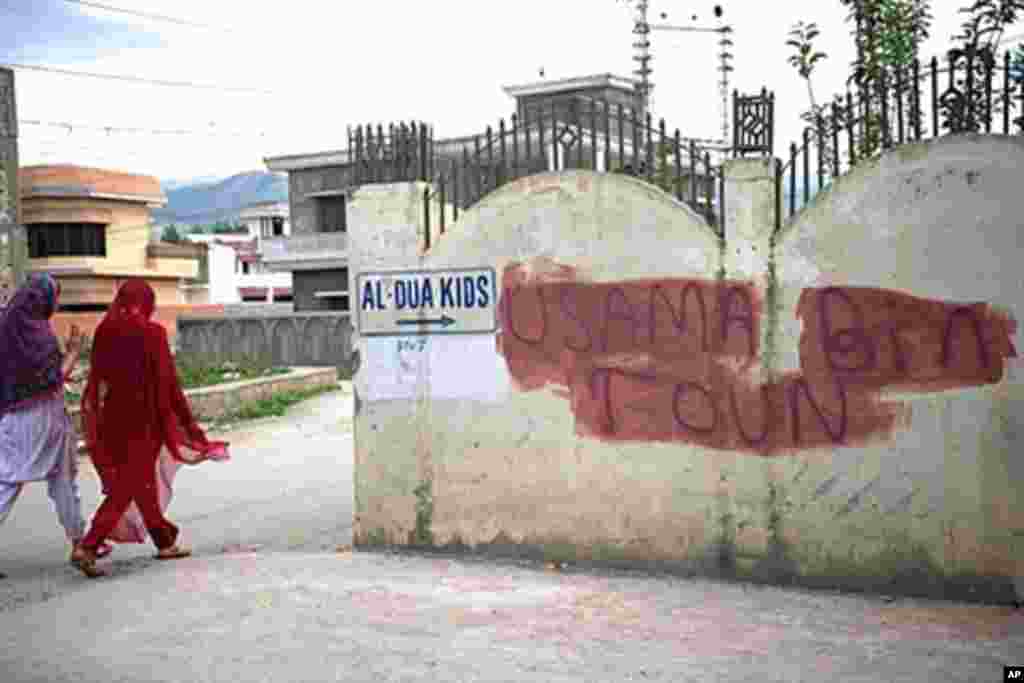Pakistani women walk past covered graffiti that reads "Usama bin Laden toun" (Osama bin Laden town) in Abbottabad on May 6, 2011, where bin Laden was found and killed by US commandos on May 2 (AFP).