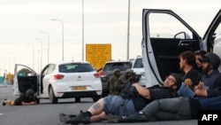 Sejumlah jurnalis berlindung di balik mobil-mobil ketika tentara Israel bertahan saat bentrok dengan para militan Hamas di Gevim Kibbutz, dekat perbatasan Gaza, 7 Oktober 2023. (Foto: Oren Ziv/AFP)