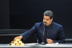 FILE - Venezuela's President Maduro touches a gold bar as he speaks during a meeting with the ministers responsible for the economic sector in Caracas, March 22, 2018.