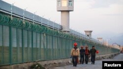 Beberapa pekerja melewati gedung yang dijadikan sebagai "pusat pendidikan kejuruan" bagi Muslim Uighur di Dabancheng, Xinjiang, China (foto: dok). 