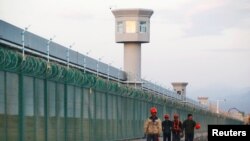 Trabalhadores passam em frente à vedação do que é conhecido oficialmente como centro vocacional em Dabancheng, região autónoma de Xinjiang Uighur , China, 4 set, 2018.(arquivo)