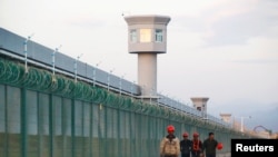 FILE: Workers walk by the perimeter fence of what is officially known as a vocational skills education center in Dabancheng in Xinjiang Uighur Autonomous Region, China, Sept. 4, 2018.