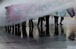 Demonstrators are sprayed by a water cannon by security forces during a protest against Chile's government in Valparaiso, Chile, Dec. 4, 2019.