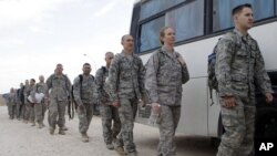 US service members queue to board a bus as they begin their journey home at al-Asad Air Base west of Baghdad, Iraq, November 1, 2011.