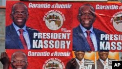 A man puts up electoral posters on a wall in a street of Conakry ahead of Guinea's first free election since independence in 1958., 24 Jun 2010