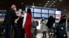Travellers wearing protective face masks stand at the Delta Air Lines ticketing desk inside Terminal 2E at Paris Charles de Gaulle airport in Roissy, France, March 12, 2020.