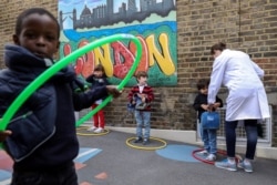 FILE - Children use hoops for social distancing at L'Ecole des Petits, an independent French bilingual school, as the coronavirus disease (COVID-19) lockdown eases in Fulham, London, June 9, 2020.