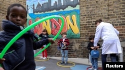 Children use hoops for social distancing at L'Ecole des Petits, an independent French bilingual school, as the coronavirus disease (COVID-19) lockdown eases in Fulham, London, June 9, 2020. 