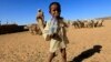 A child carries a bottle of water at a water stop near their shelter at Hajar Al-assal, north of Khartoum on March 19, 2013. 